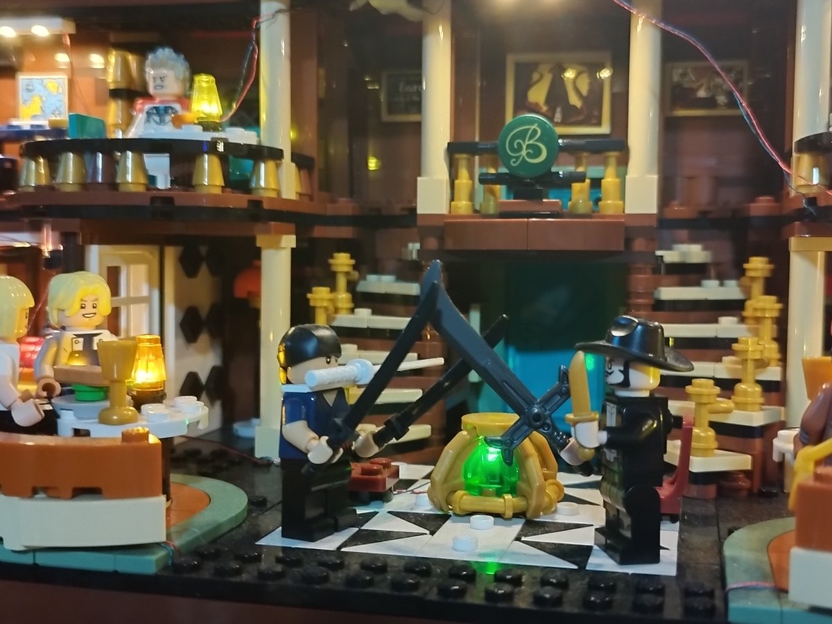 Inside the Baratie restaurant: pirates and diners at round tables under hanging lamps, with swords drawn and a green glow