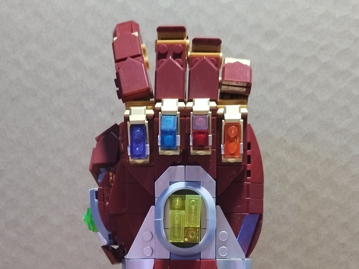 The whole Iron Man Nano Gauntlet on its black stand, with red fingers, gold gem slots and a yellow centre
