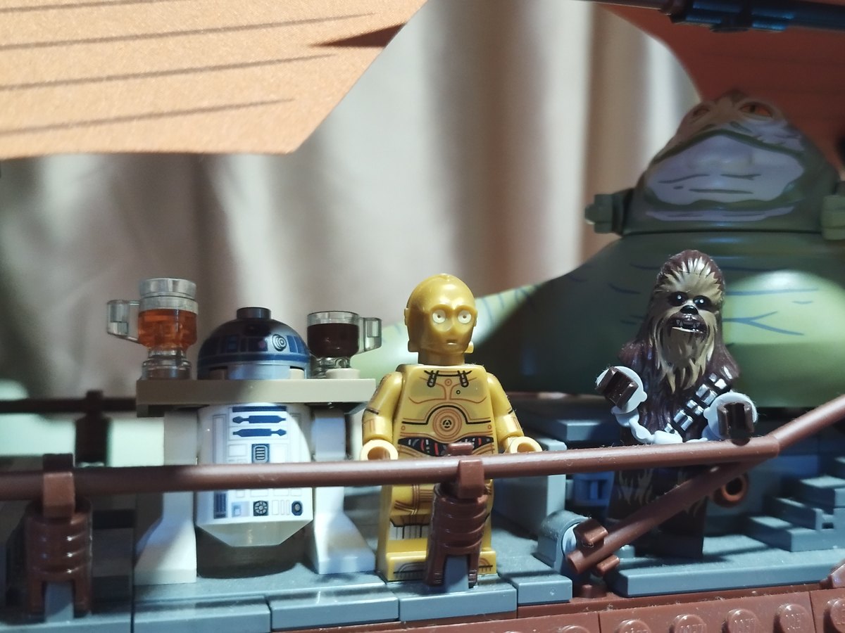 R2-D2, C-3PO and Chewbacca on the deck of the sail barge, with Jabba the Hutt behind them
