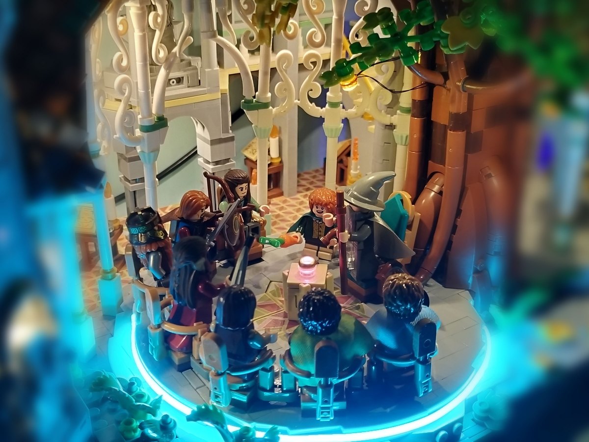 Lit Rivendell council scene: minifigures gathered around a table under white filigree arches, with a glowing teal base