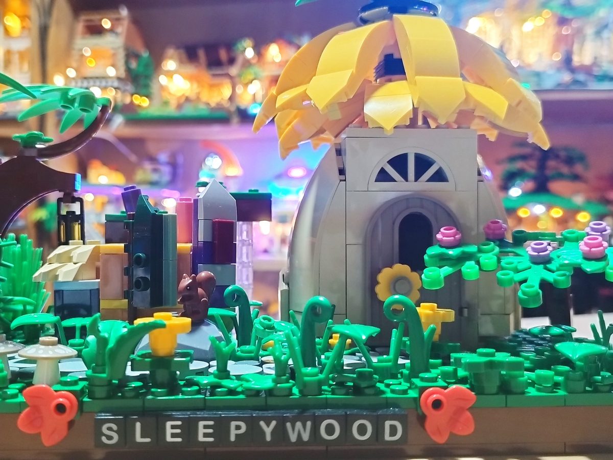 The Sleepywood diorama with its name plate, a giant yellow flower house and a green garden