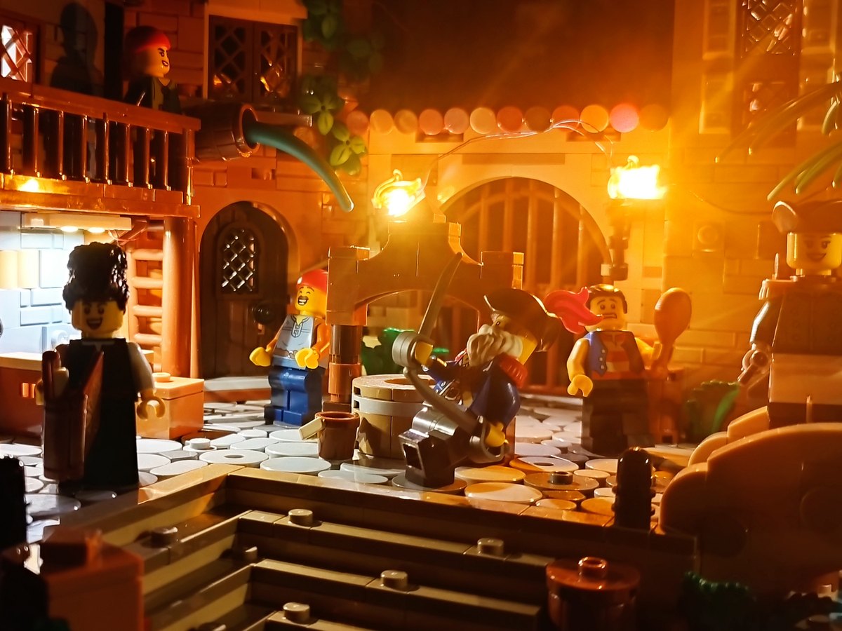 A warm lantern-lit street in the Tortuga village, with pirates beside an arched stone doorway and a balcony above